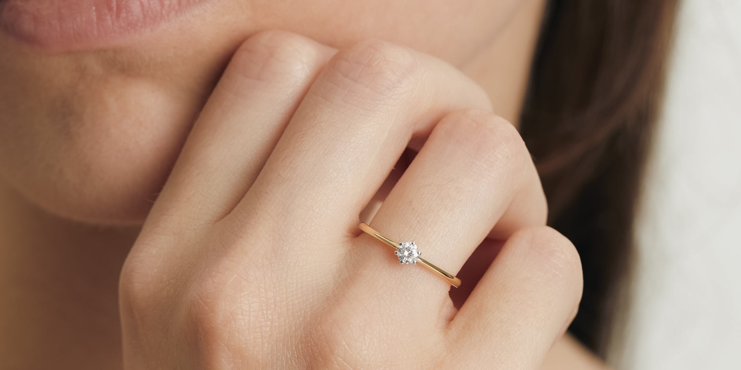 Zarter Goldring mit Solitär-Diamant am Finger getragen